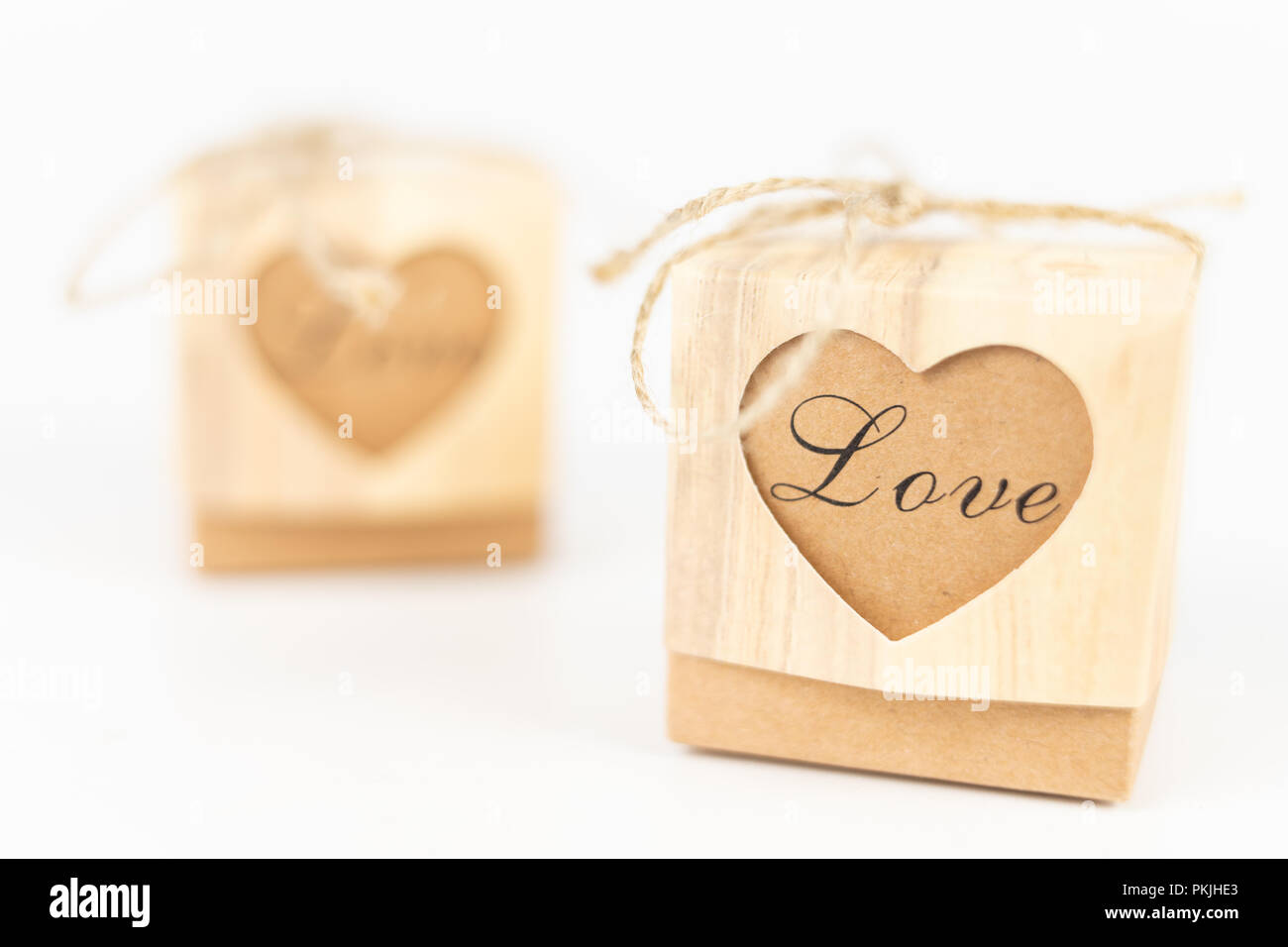 Boxes with the word love on a white table. A gift in a box with a heart cut out. White background. Stock Photo