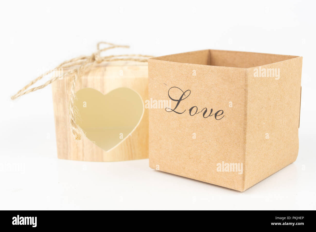 Boxes with the word love on a white table. A gift in a box with a heart cut out. White background. Stock Photo