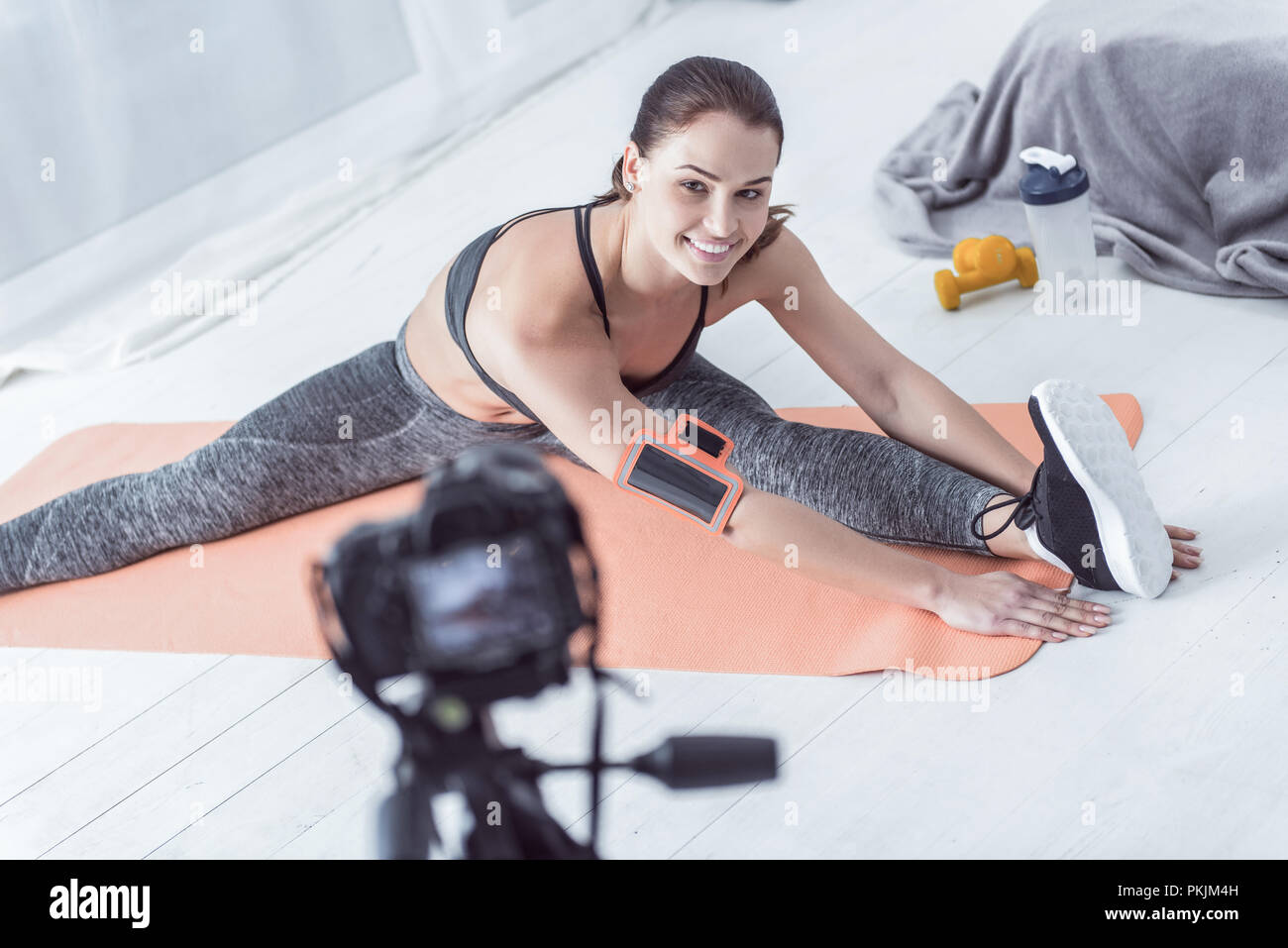 Delighted positive woman sitting on a yoga mat Stock Photo