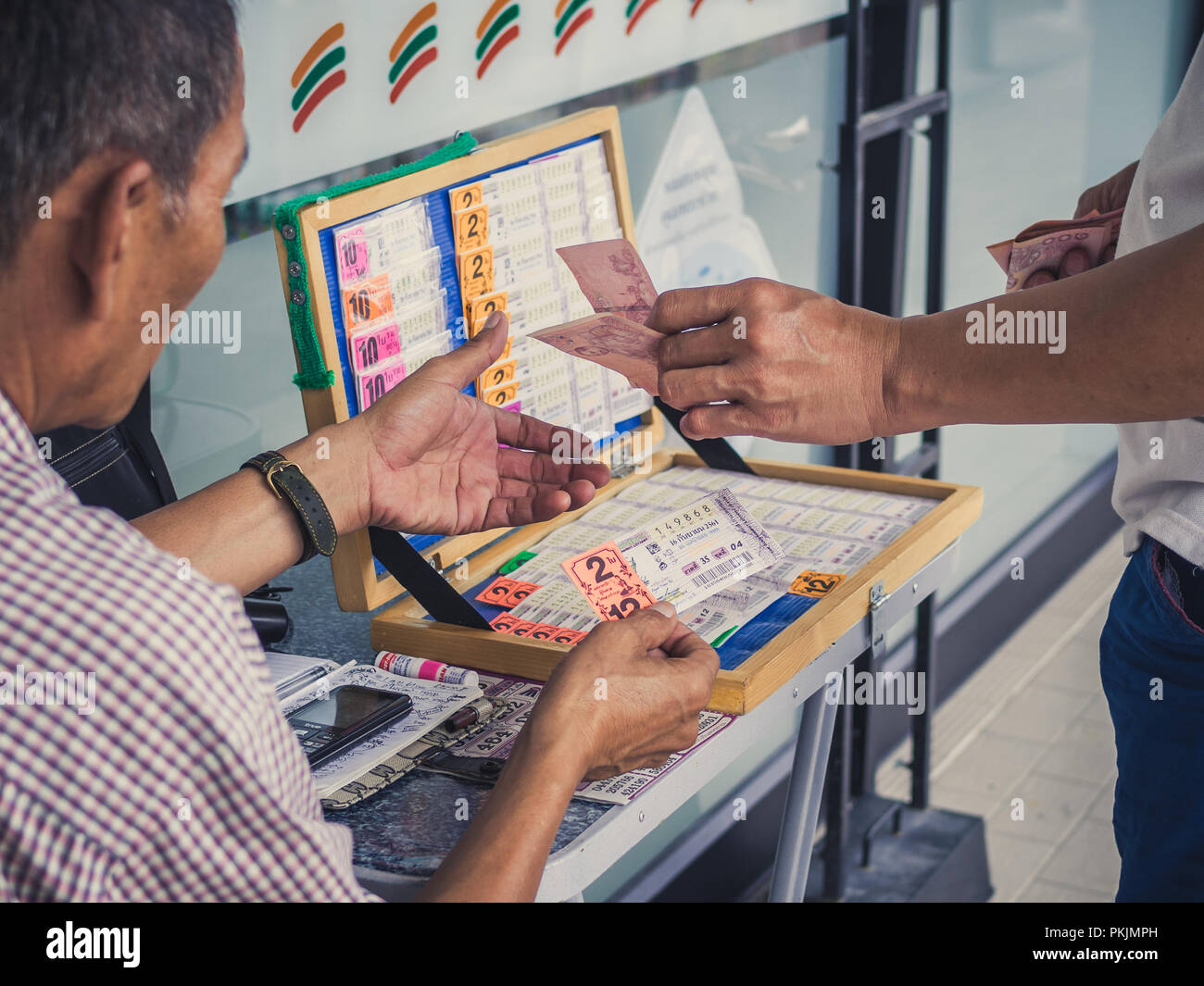 SEPTEMBER 8, 2018 :  Bangkok, Thailand : Man hand and paying two hundred Thai baht money to buy lottery from lottery seller. Stock Photo