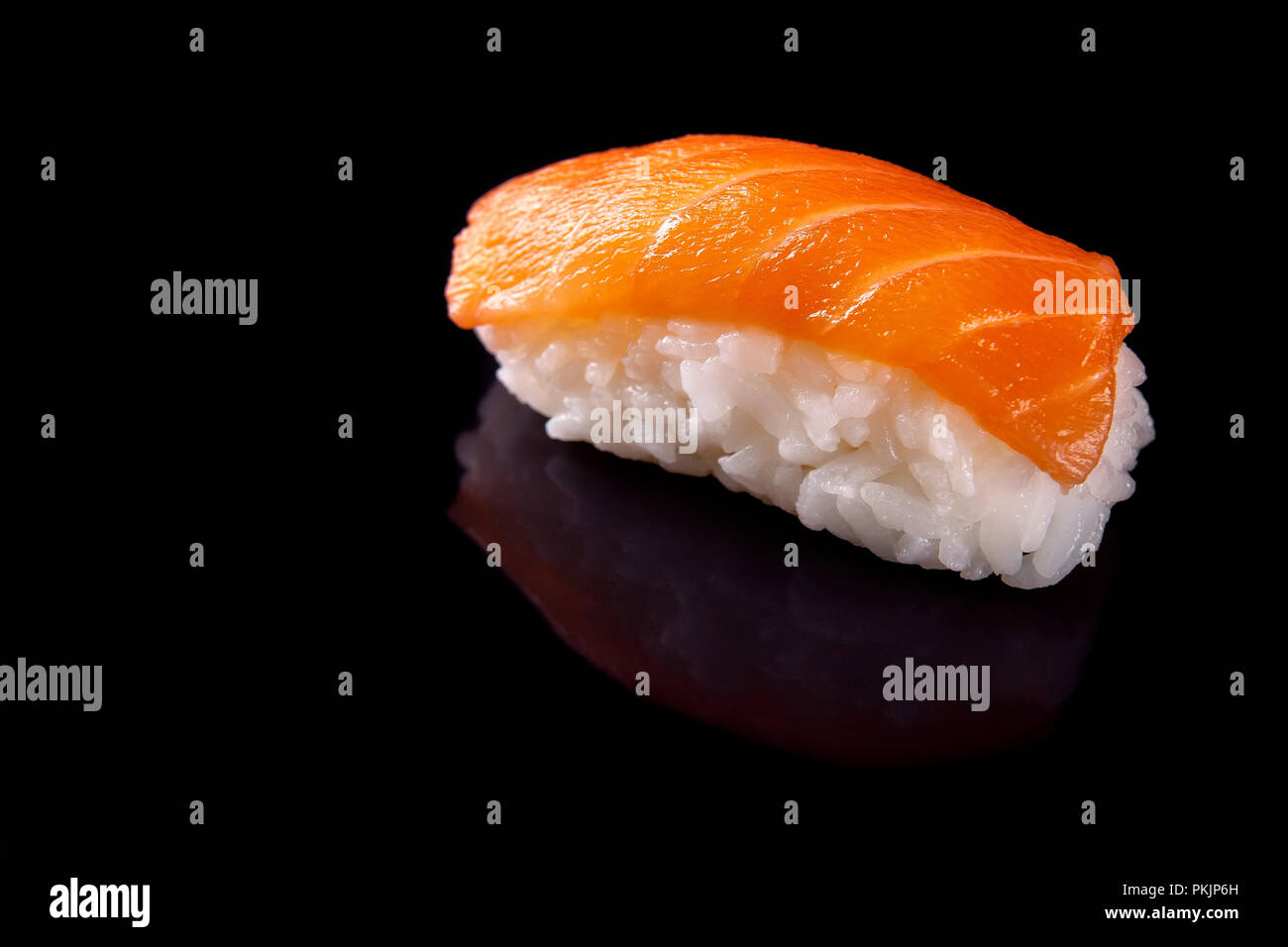 Macro shot of one sushi with salmon on black backgorund with its reflection Stock Photo