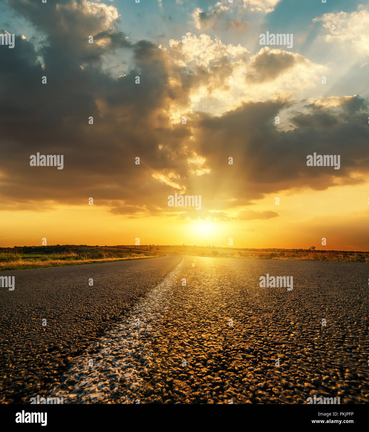 orange sunset in low dark dramatic clouds over asphalt road Stock Photo ...