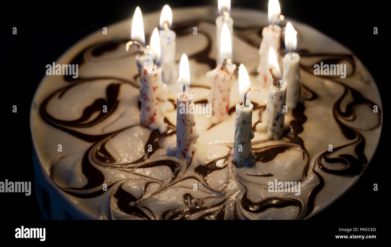 Birthday cake with colorful burning candles in dark Stock Photo - Alamy