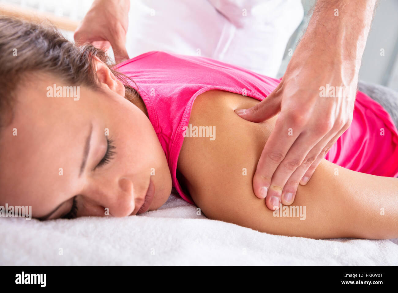 Close-up Of A Therapist's Hand Giving Shoulder Massage To Relaxed Female Patient Stock Photo