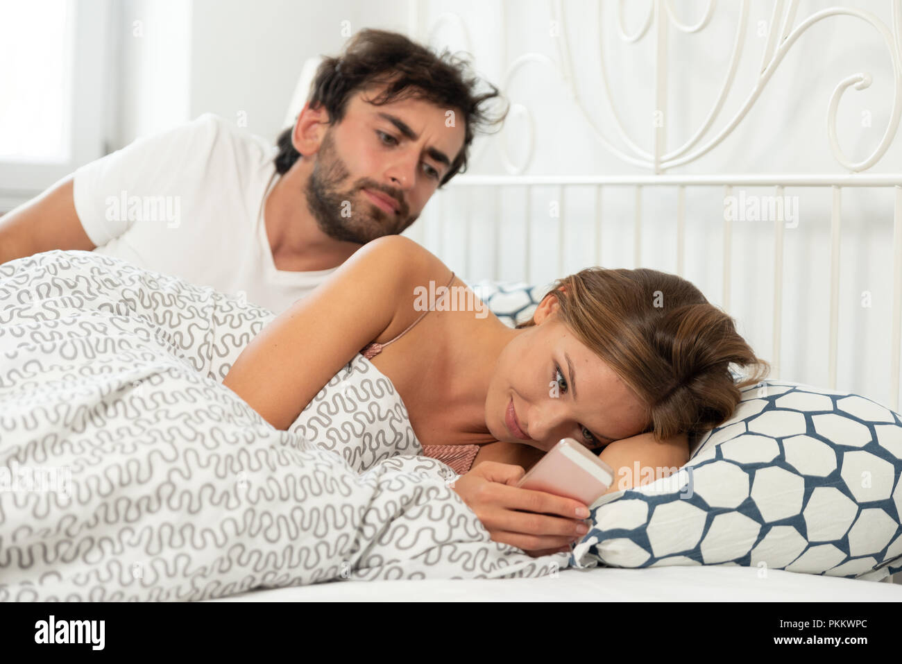 Jealous man checks what a woman with a phone in hand is doing. Concept of relationship, betrayal and jealousy Stock Photo