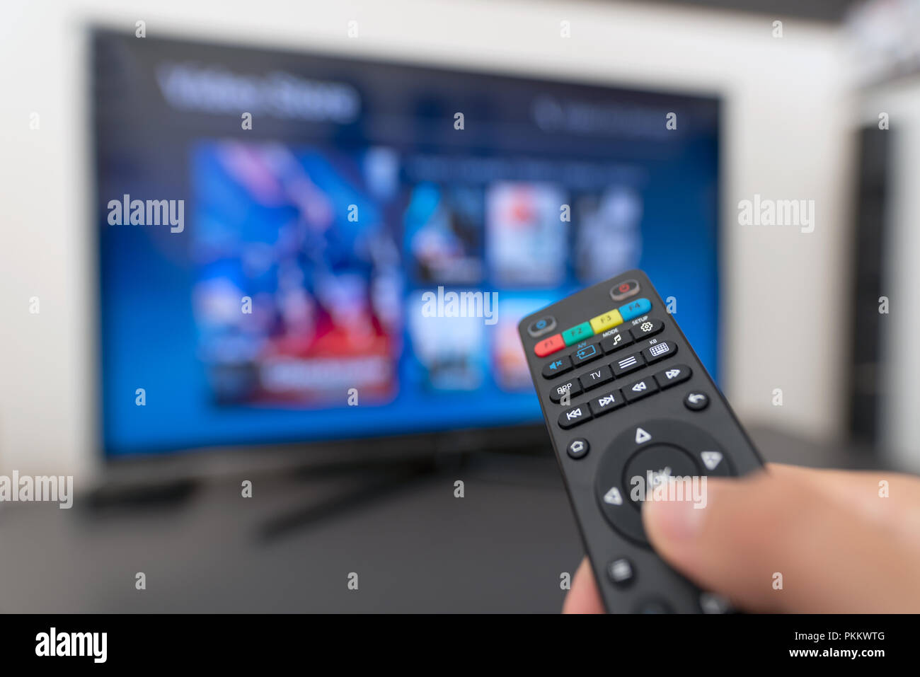 Multimedia streaming concept. Hand holding remote control. Video on demand Stock Photo