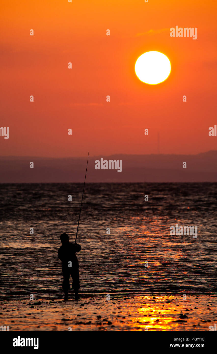 Sea angler at sunset on the North Wales coast at Llandudno Stock Photo