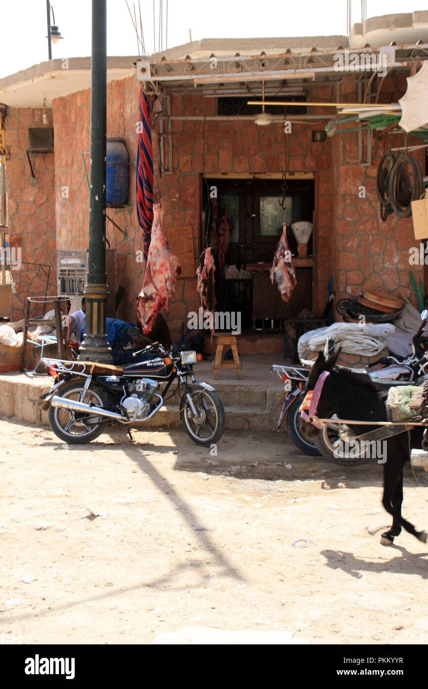 Parked old and a passing donkey cart front of a butcher's shop with red meat hanging from ceiling. Siwa, Siwa Oasis, Egypt Stock Photo - Alamy