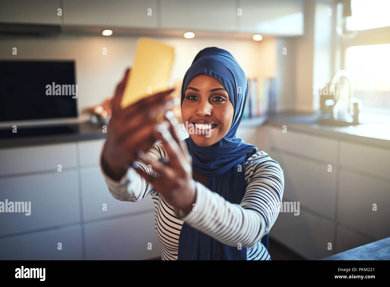 Smiling young Arabic woman wearing a hijab taking selfies with her ...