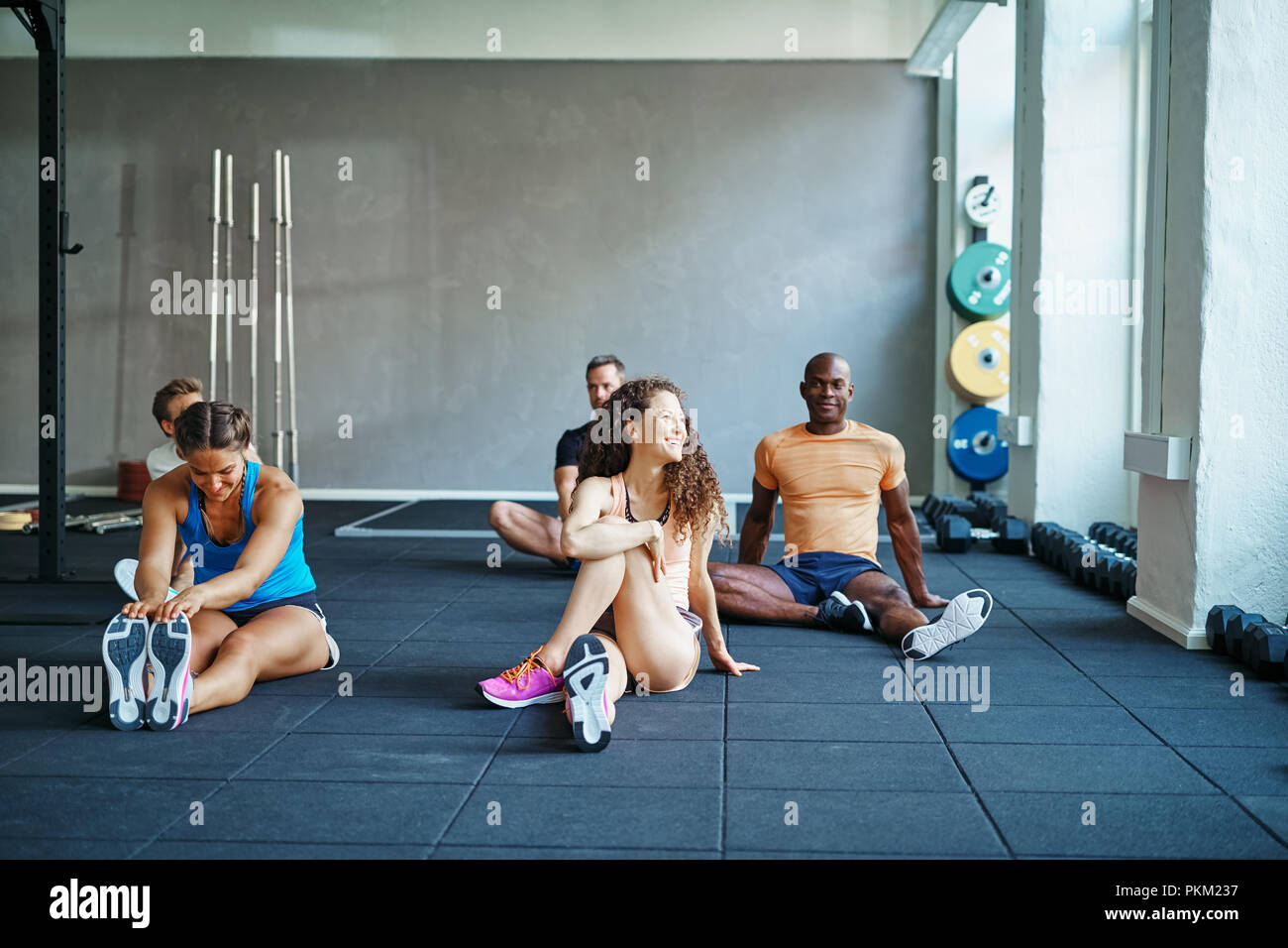 Diverse group of fit people in sportswear stretching together before a class at a health club Stock Photo