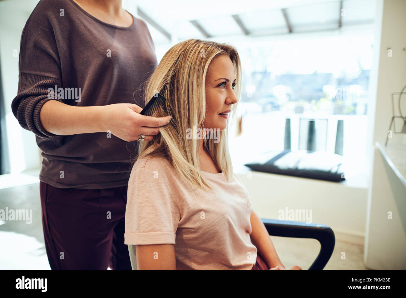 Smiling Young Woman Sitting In A Salon Chair Having Her Long