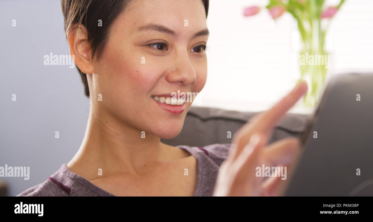 Asian woman using tablet on sofa Stock Photo - Alamy