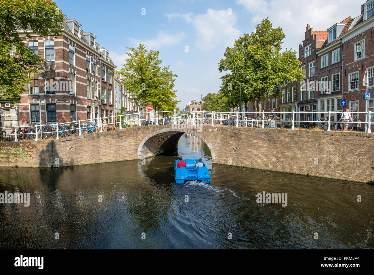 Father and son on a blue water bike sail under the bridge in a canal of Delft, the Netherlands. Stock Photo