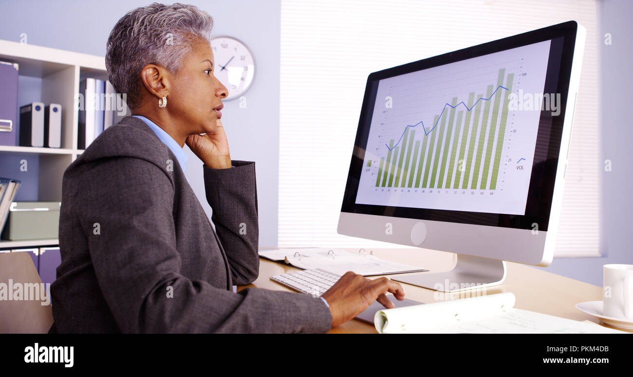 Senior African businesswoman talking on phone and working in office ...