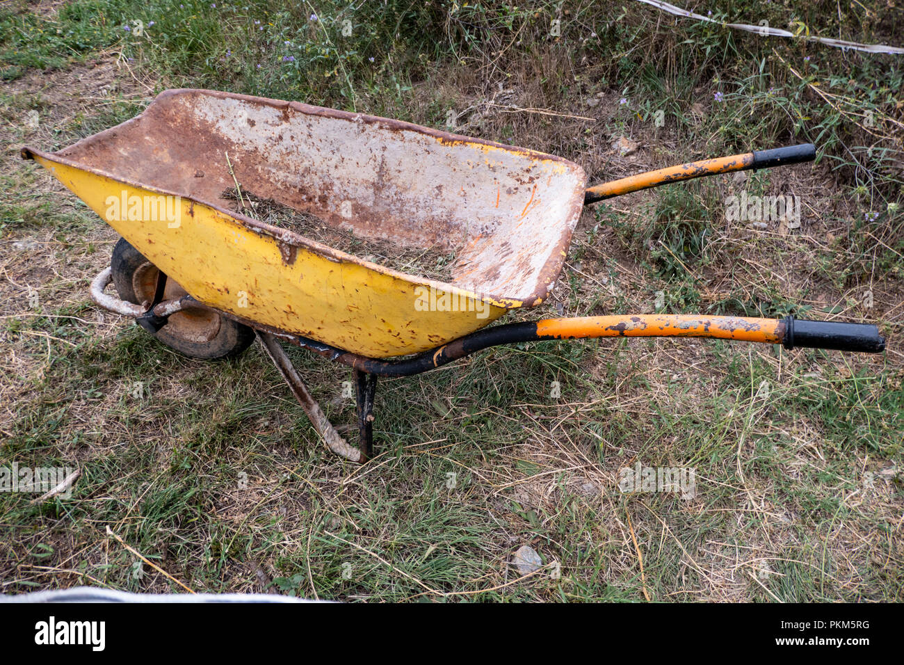An old metal wheelbarrow painted yellow Stock Photo Alamy