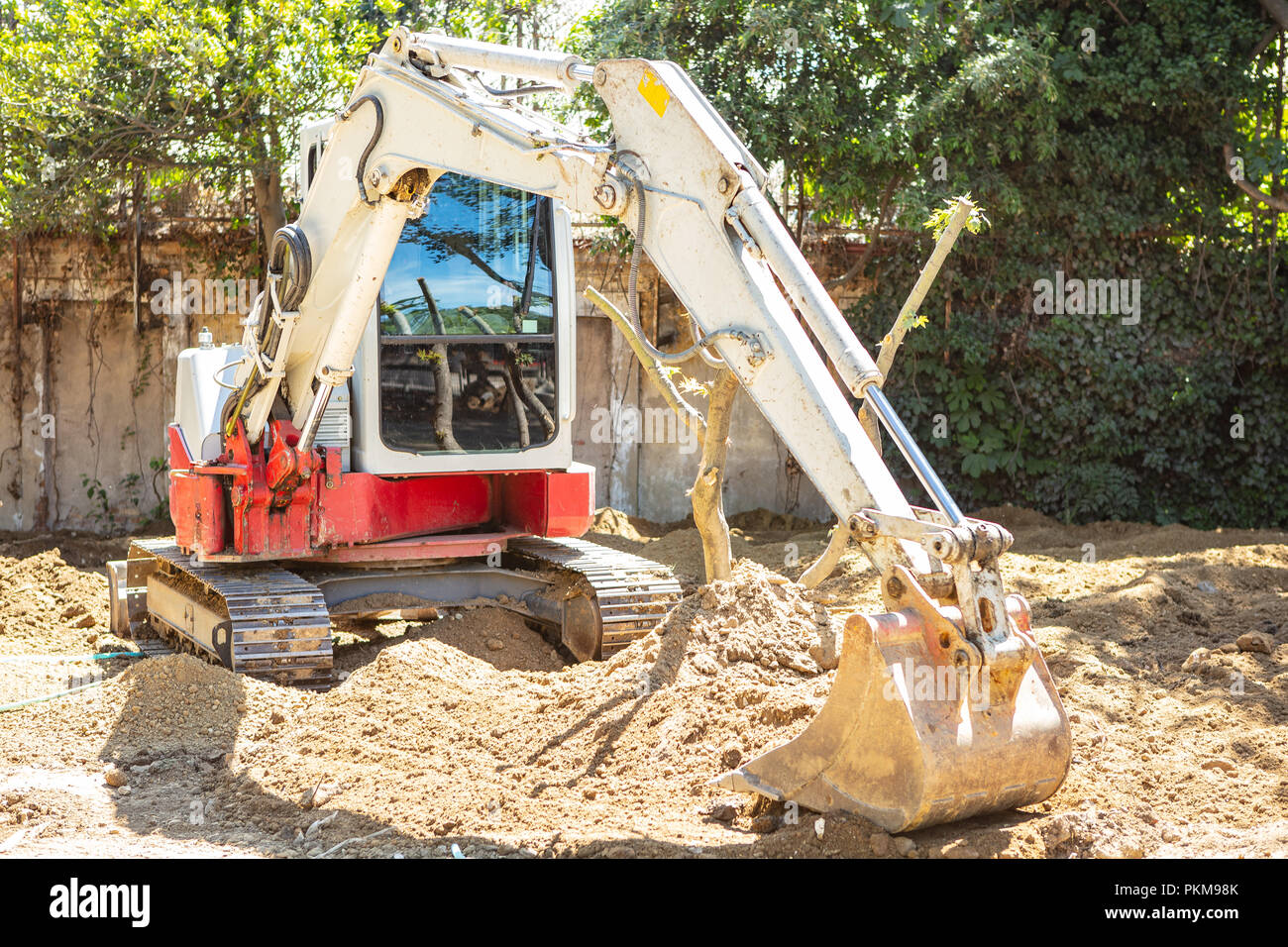 Excavator, backhoe working on soil for clear the area beside trees for new park building Stock