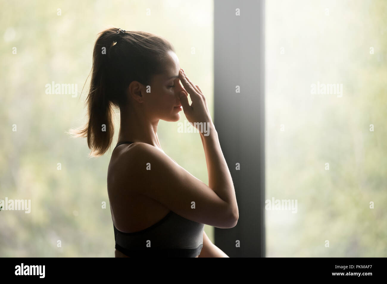 Young sporty woman doing Alternate Nostril Breathing Stock Photo