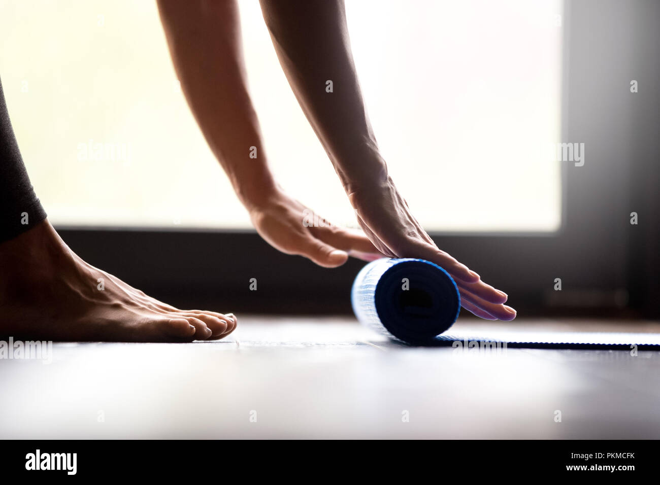Young woman rolling fitness mat, hands close up  Stock Photo