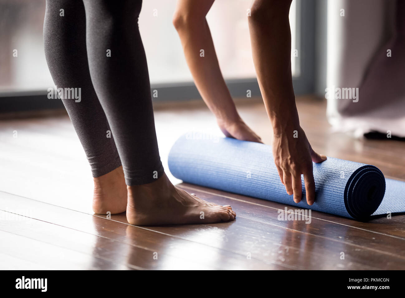 Girl rolling yoga mat for meditation or fitness at home Stock Photo