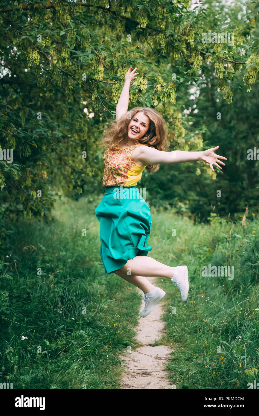 Single Young Pretty Plus Size Caucasian Happy Smiling Laughing Girl Woman Jumping In Summer Green Forest. Fun Enjoy Outdoor Summer Nature. Stock Photo