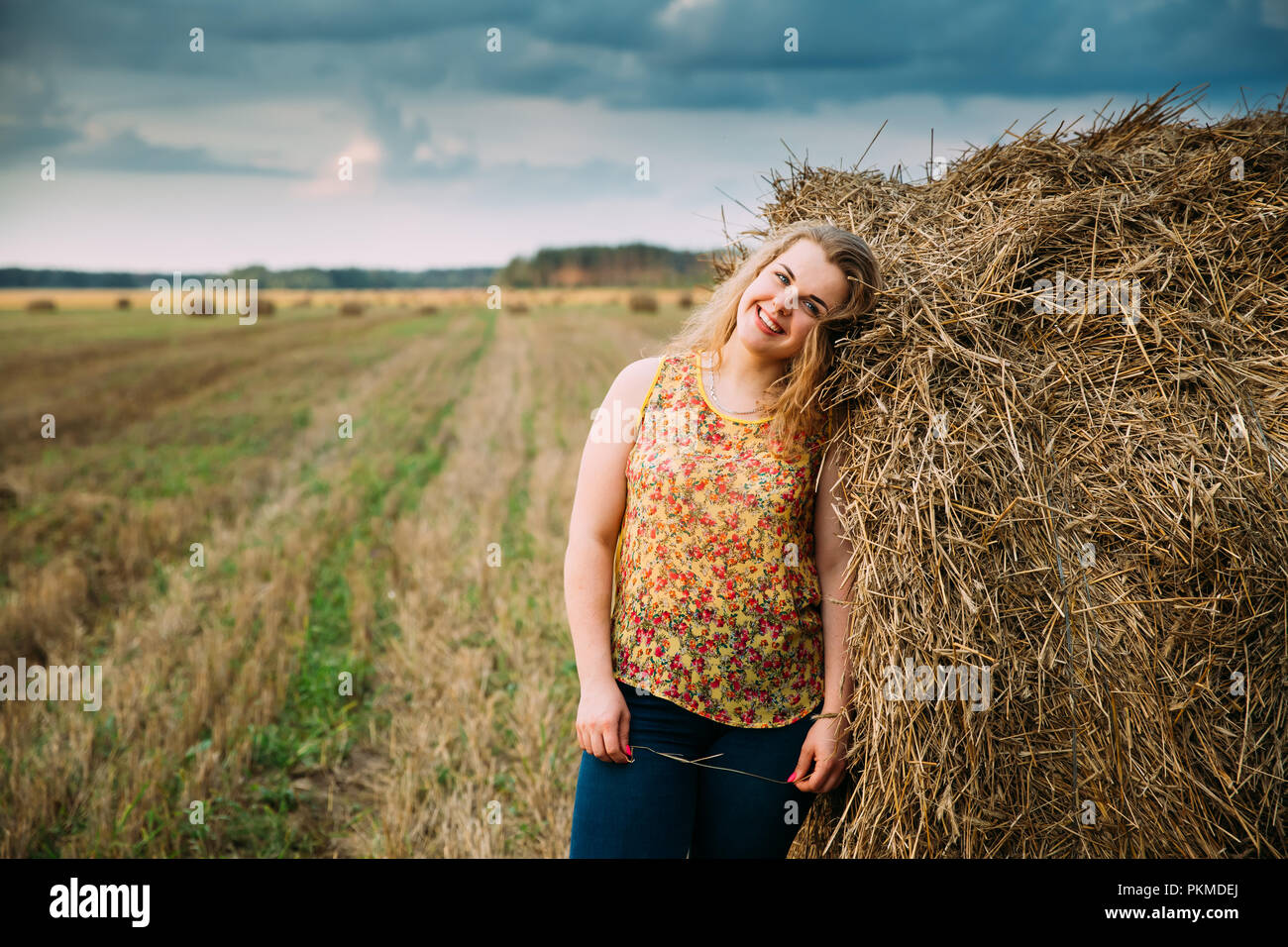 Portrait Beautiful Plus Size Young Woman Standing Near Hay Bale In Summer Field. Stock Photo