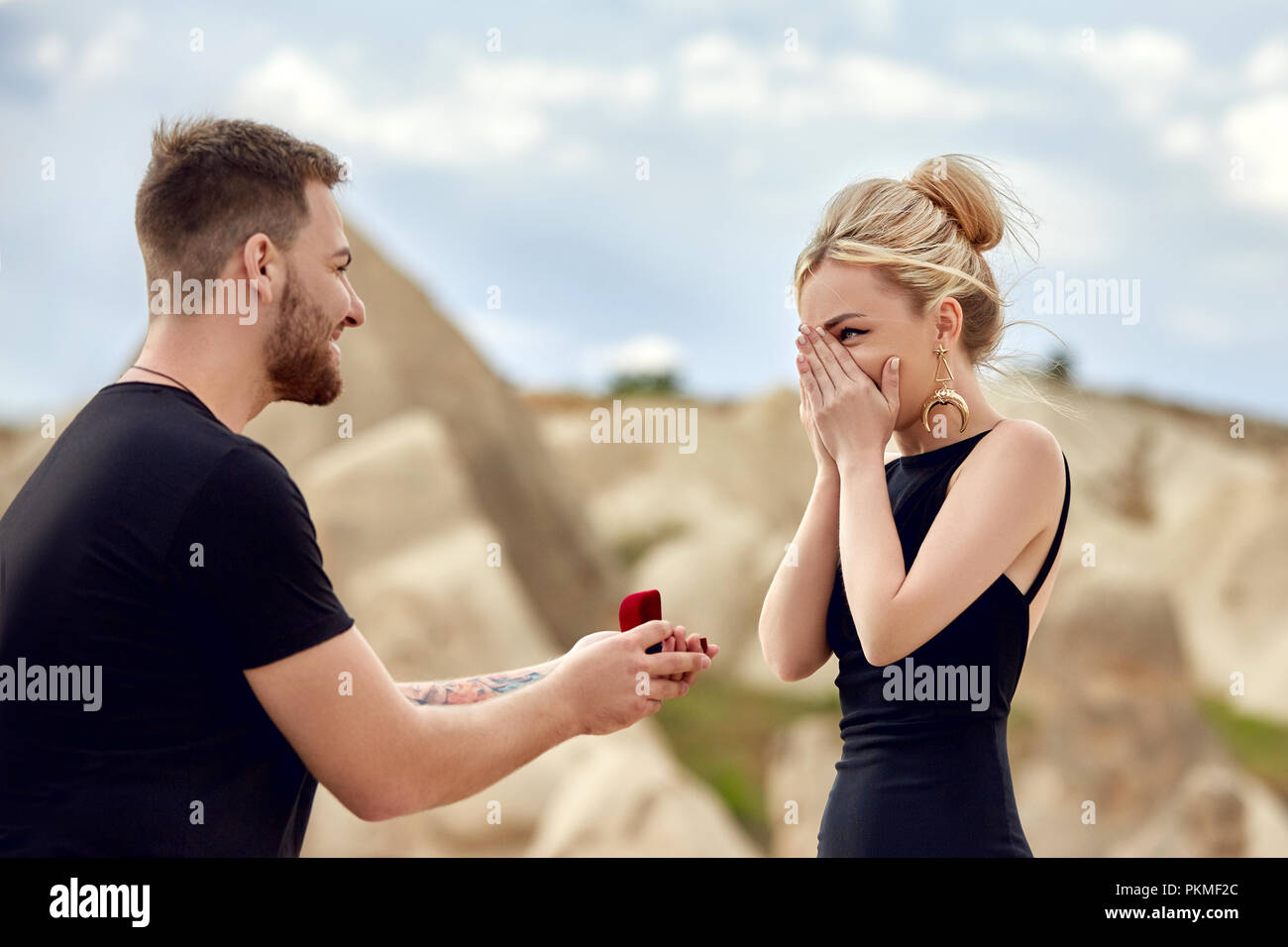Man makes a marriage proposal to his girlfriend. Engagement of a couple in love in nature. The guy wears a wedding ring on a woman's finger. Happy emo Stock Photo