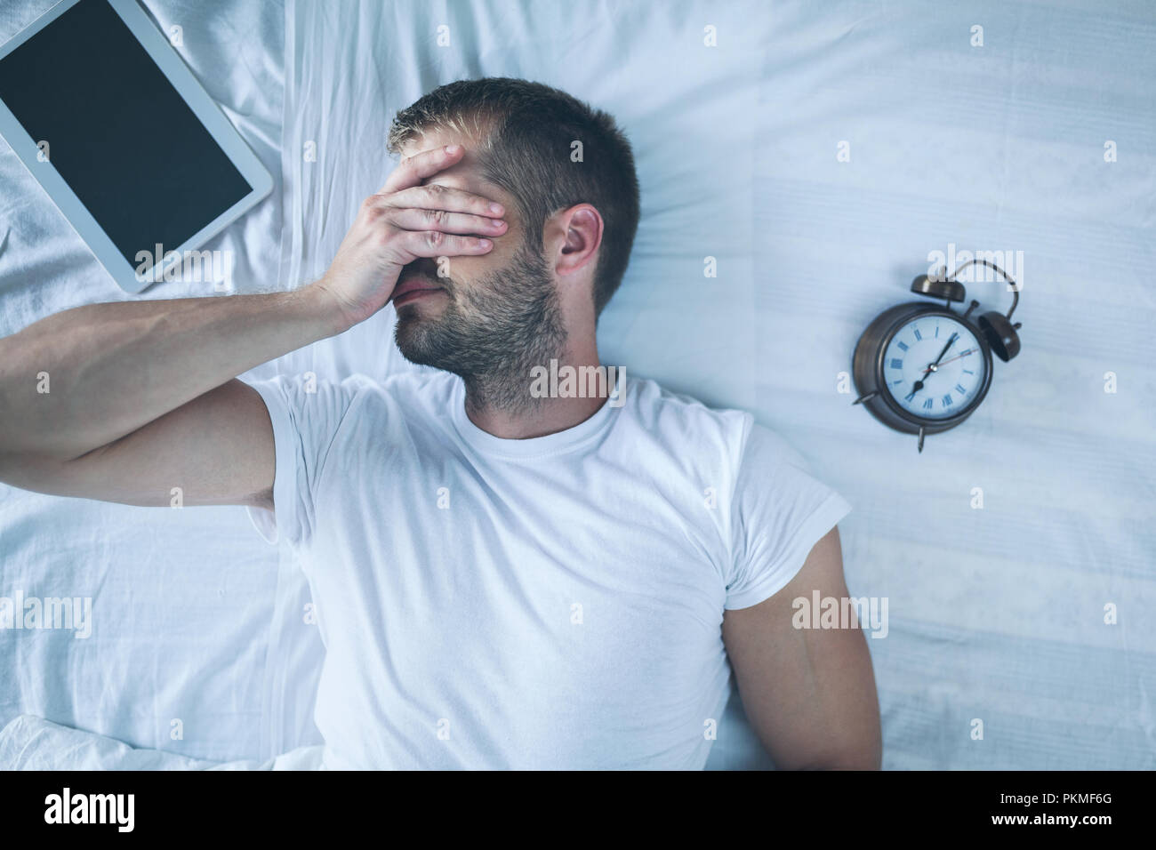 Tired man sleeping on bed after using his digital tablet Stock Photo