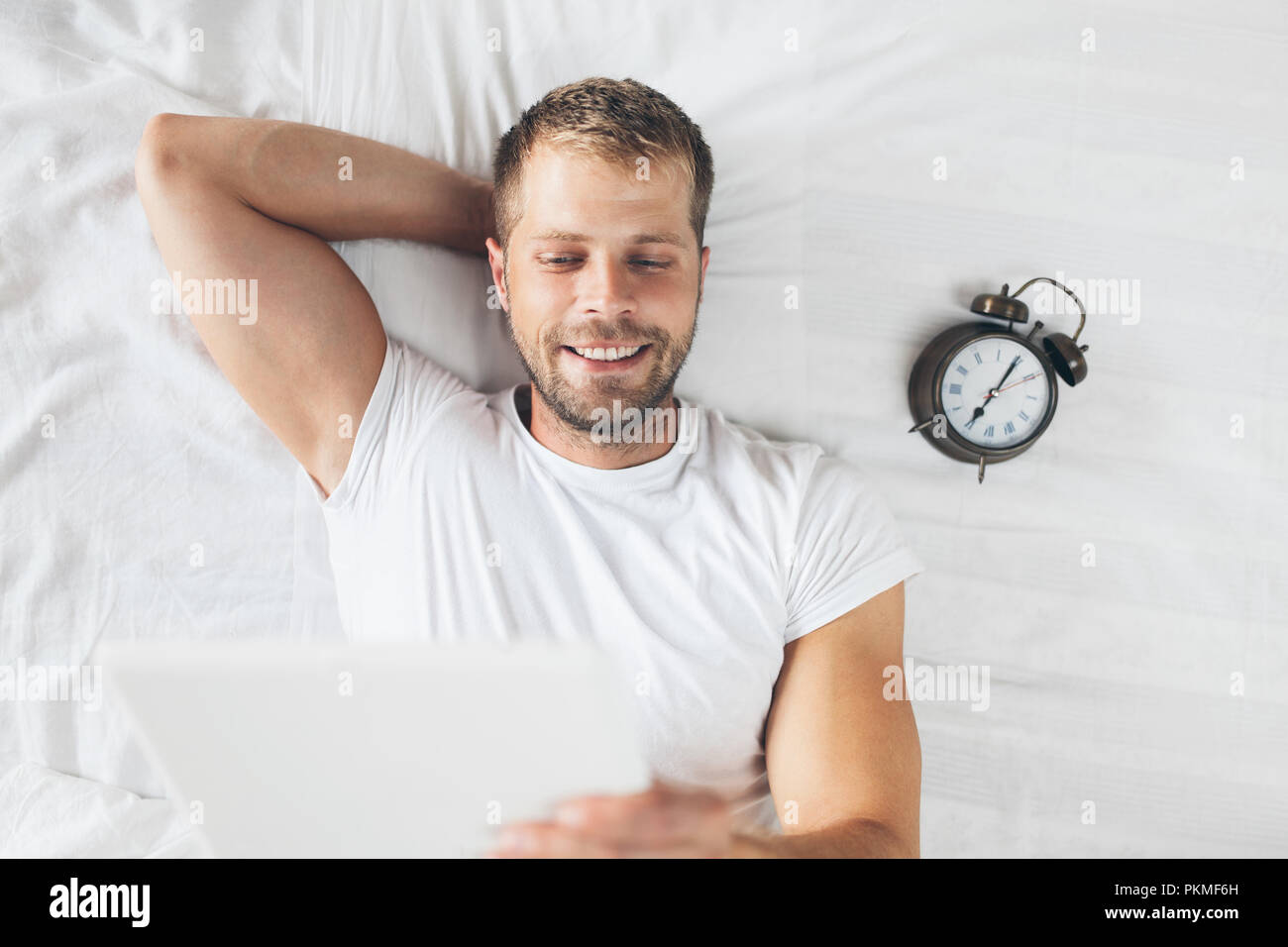 Handsome man using a digital tablet in bed at home Stock Photo