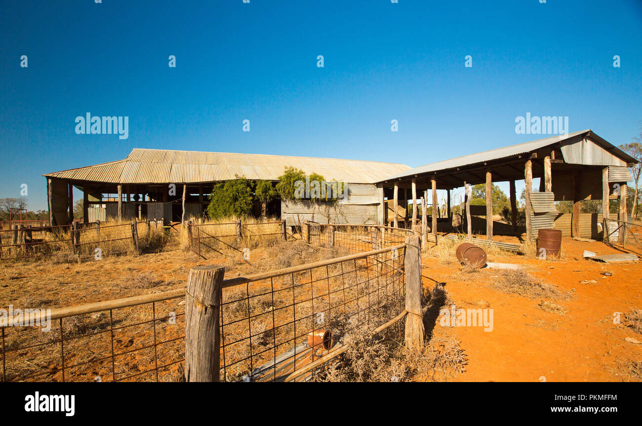 Panoramic view of abandoned sheep shearing shed on bare red soil and