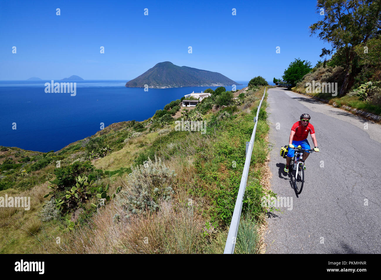 Cyclist at Punta del Legno Nero at Quattropani overlooking the island of Salina, Lipari, Aeolian Islands or Aeolian Islands Stock Photo