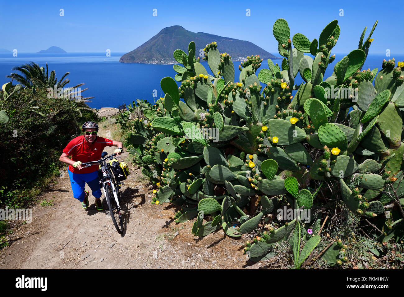 Cyclist at Punta del Legno Nero at Quattropani overlooking the island of Salina, Lipari, Aeolian Islands or Aeolian Islands Stock Photo