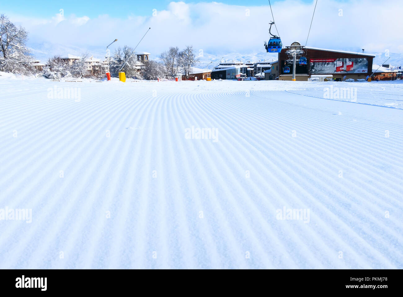 Bansko, Bulgaria - February 28, 2018: Close-up groomed snow at Bansko resort, panorama with ski slope and cable car lift Stock Photo