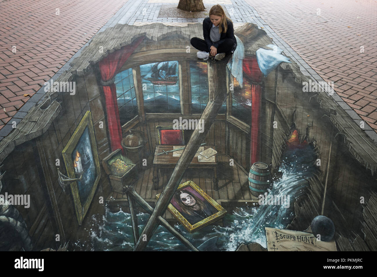 Jessica Rose sits atop a 3D anamorphic canvas art work along Upper New Street, Birmingham. Stock Photo