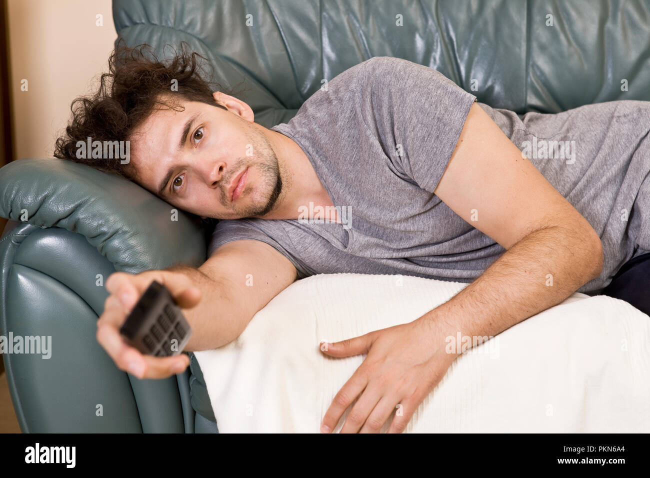 A young man watches television and changes channels while relaxing Stock Photo