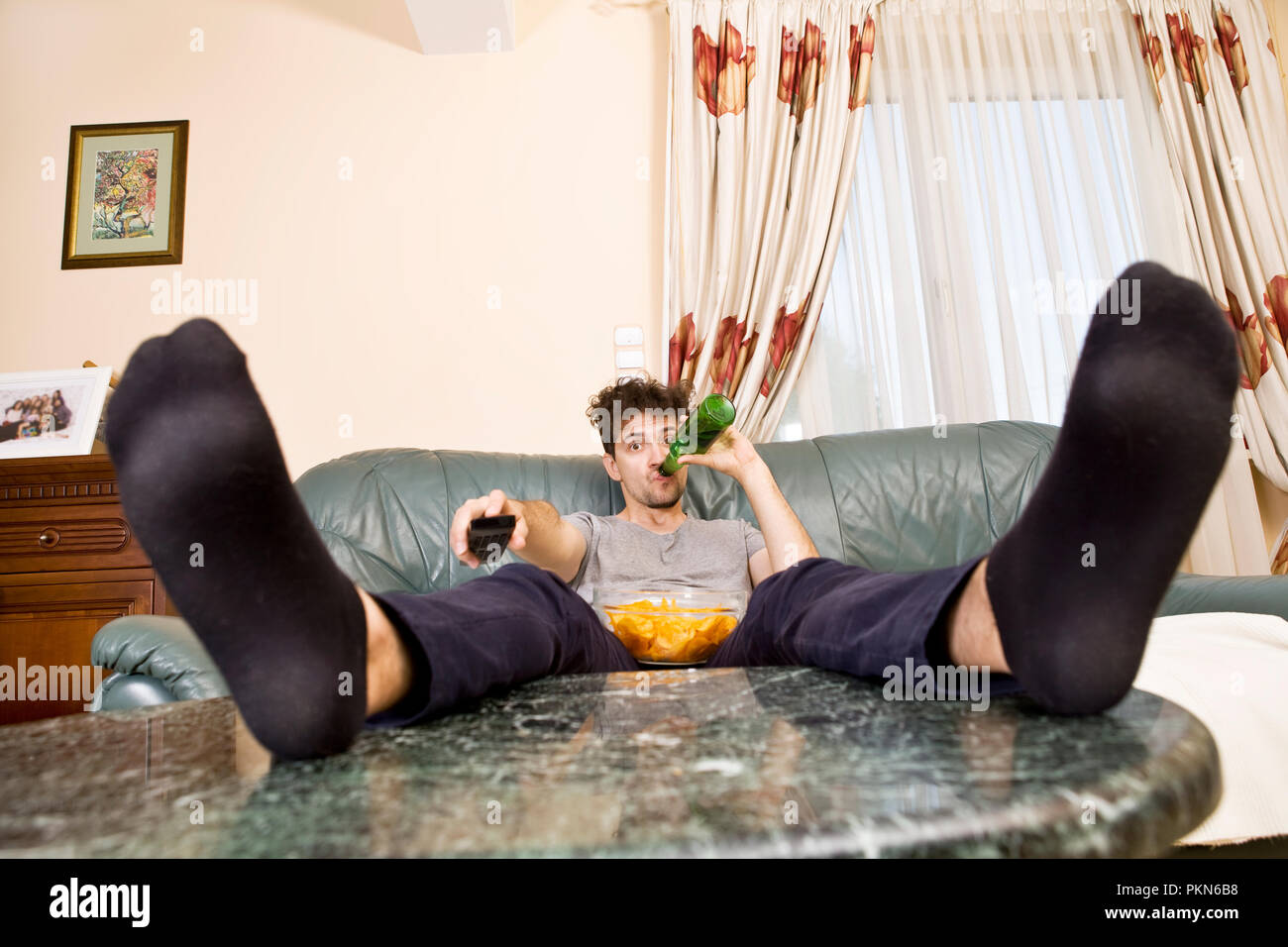 A young man watches television and changes channels while relaxing Stock Photo