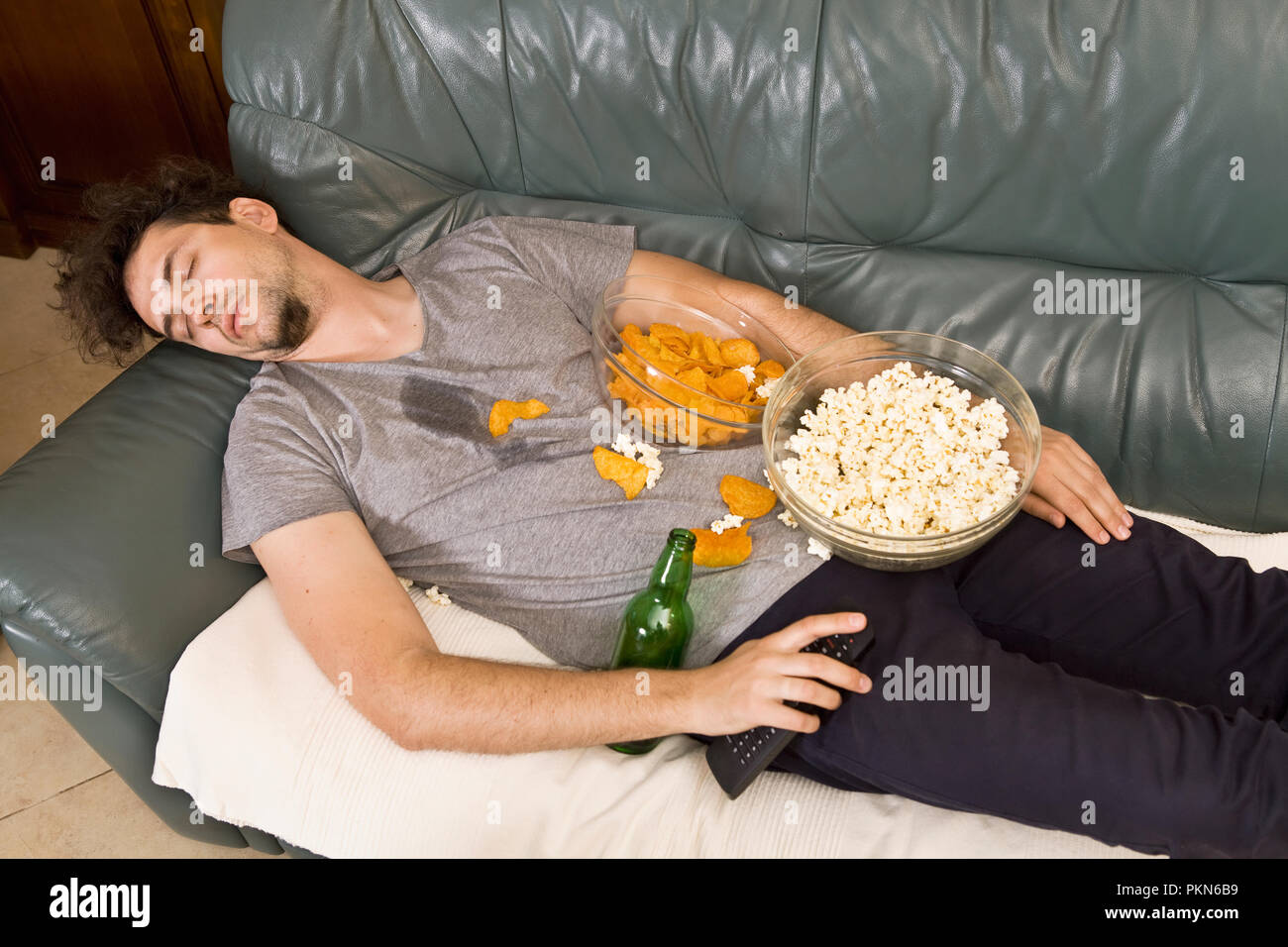 A man sleeping on a couch in a mess of junk food Stock Photo Alamy