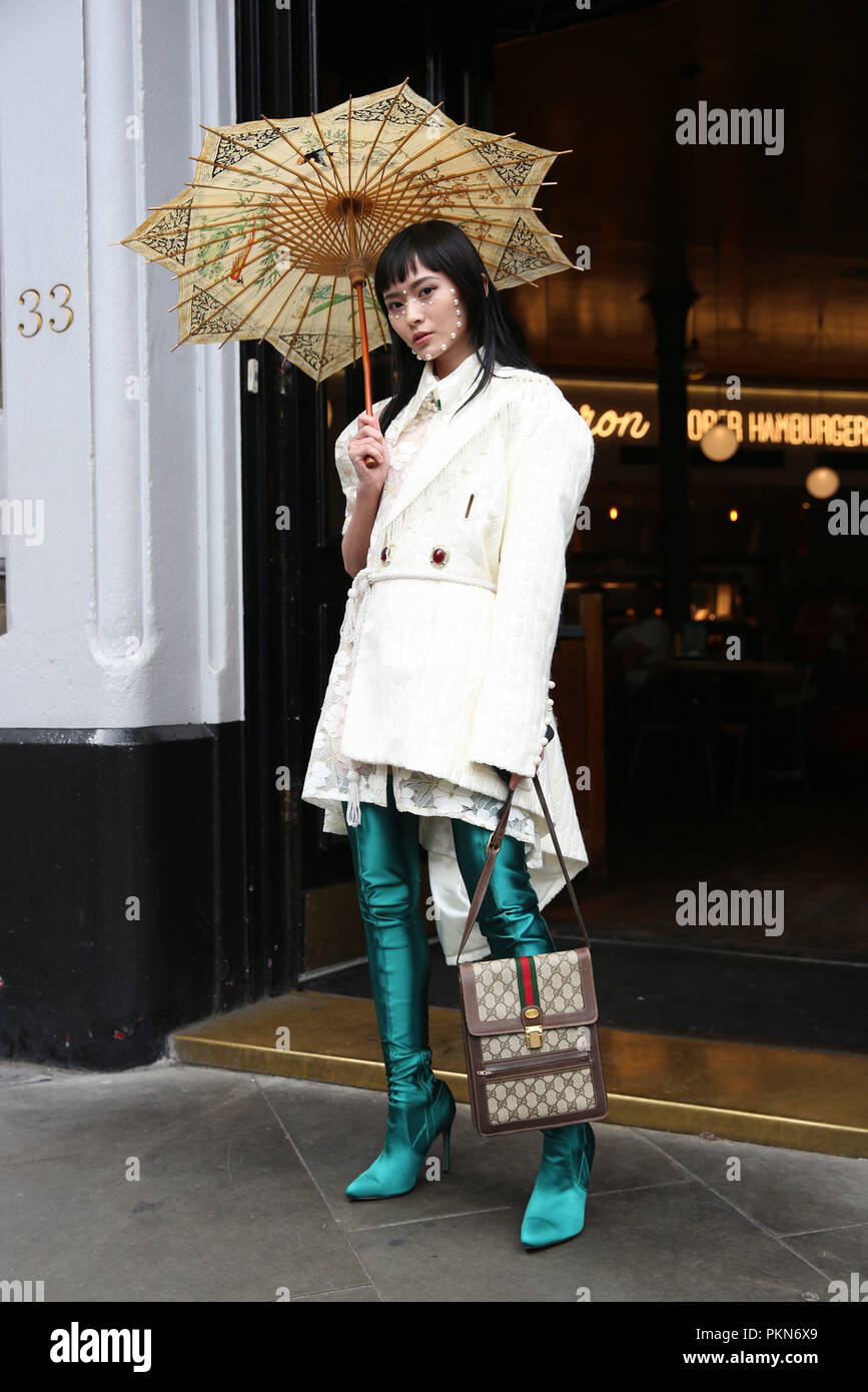 Fashion Blogger Freya Sinyu Siu, from China, wears The Seventh Tail coat, Moyasusu dress, ASOS boots, and vintage bag and umbrella during the London Fashion Week September 2018. PRESS ASSOCIATION. Picture date: Friday September 14, 2018. Photo credit should read: Isabel Infantes/PA Wire Stock Photo