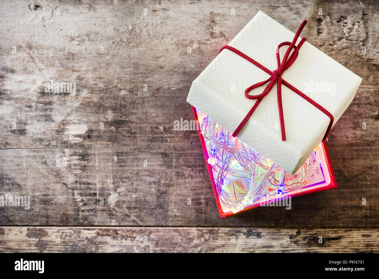 Christmas light in to red gift box on wooden table. Top view. Copyspace ...