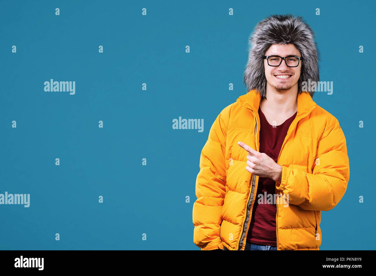 Portrait of happy young man in warm clothing on color background. Ready for winter vacation Stock Photo