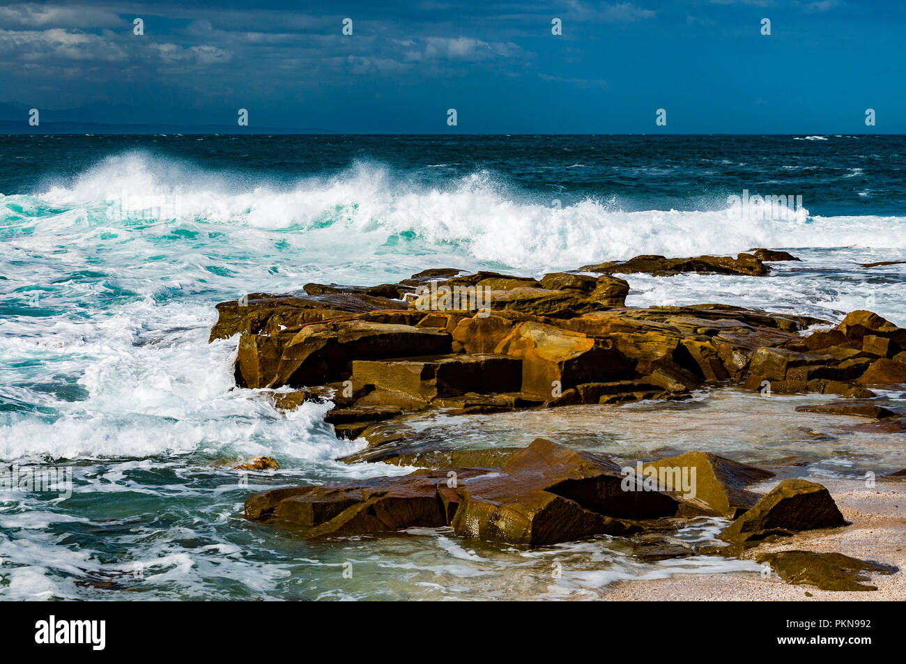 Small waves crashing on brown rocks in the South Atlantic, South Africa Stock Photo