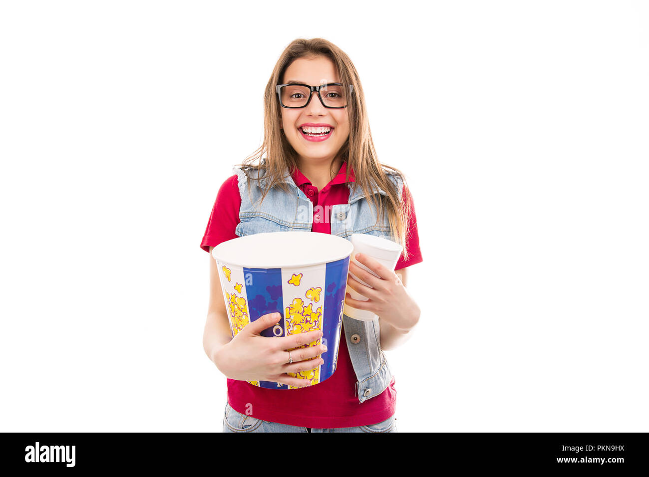 Cheerful bright woman in glasses holding bucket of popcorn and soda cup being ready for movie Stock Photo