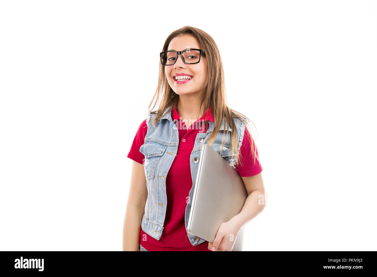 Pretty young woman in eyeglasses holding laptop and smiling at camera isolated on white background Stock Photo