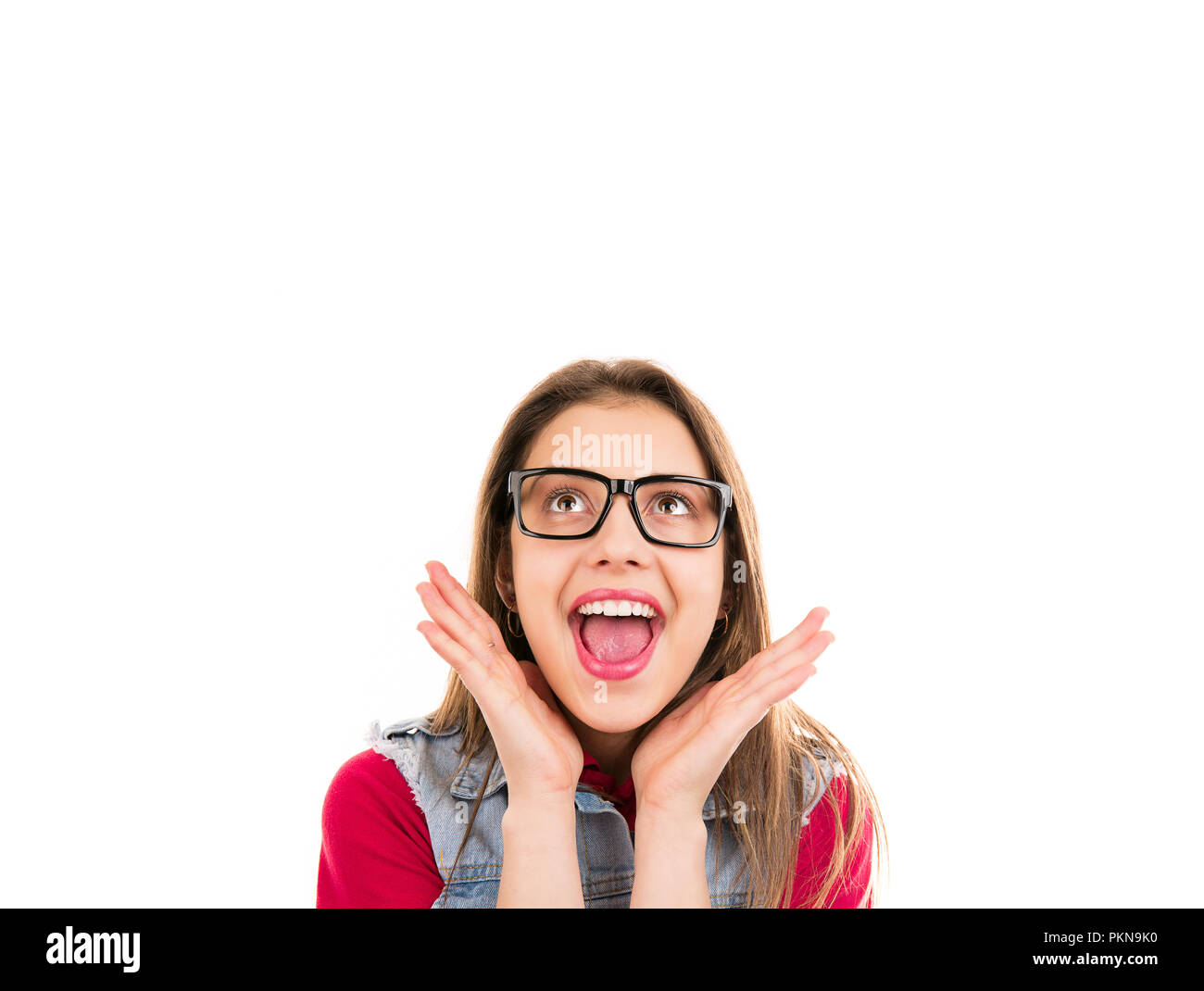 Bright excited young woman in glasses looking up in happiness isolated on white background Stock Photo