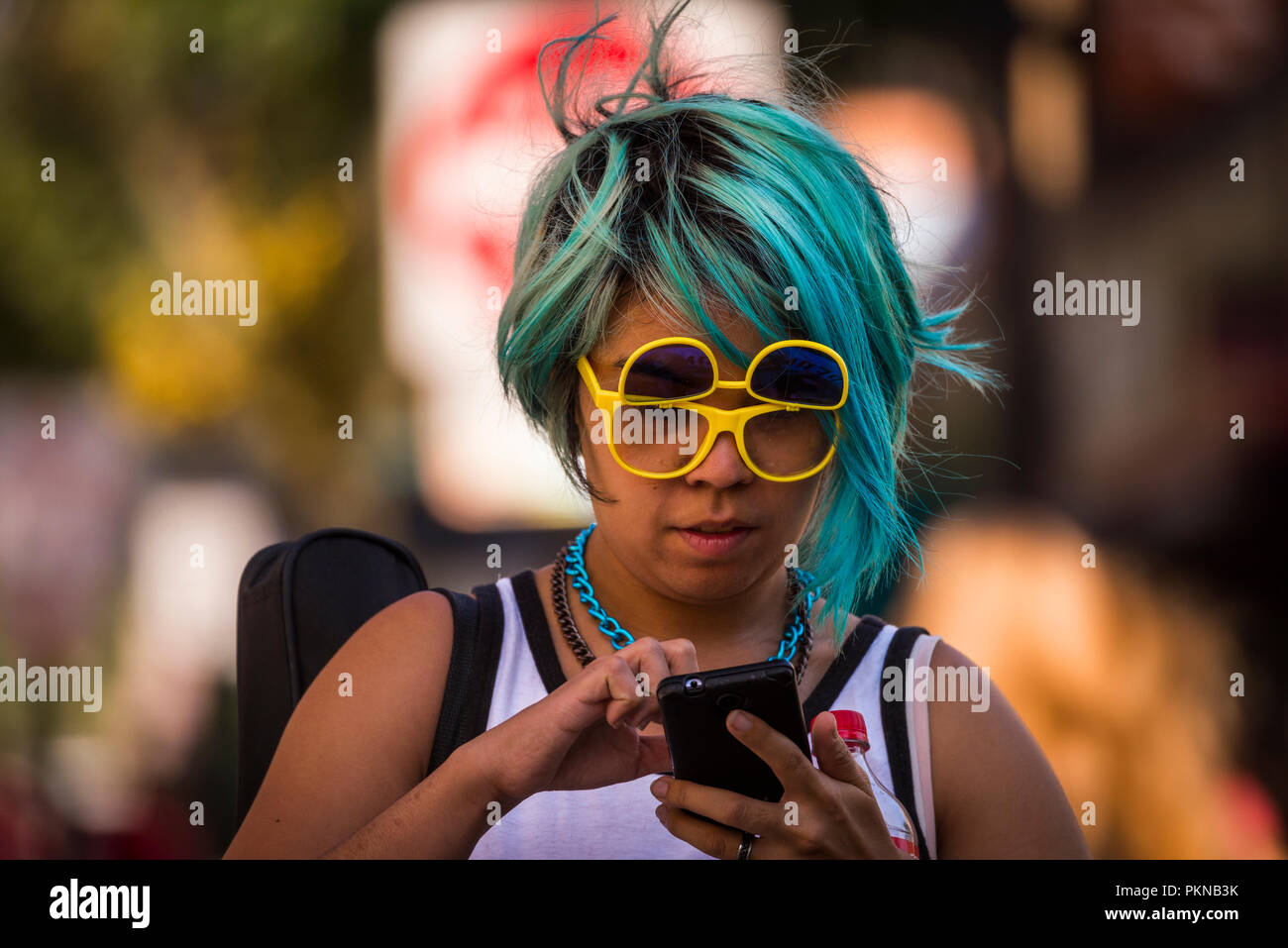 Woman with fuchsia hair wearing yellow sun glasses. Stock Photo