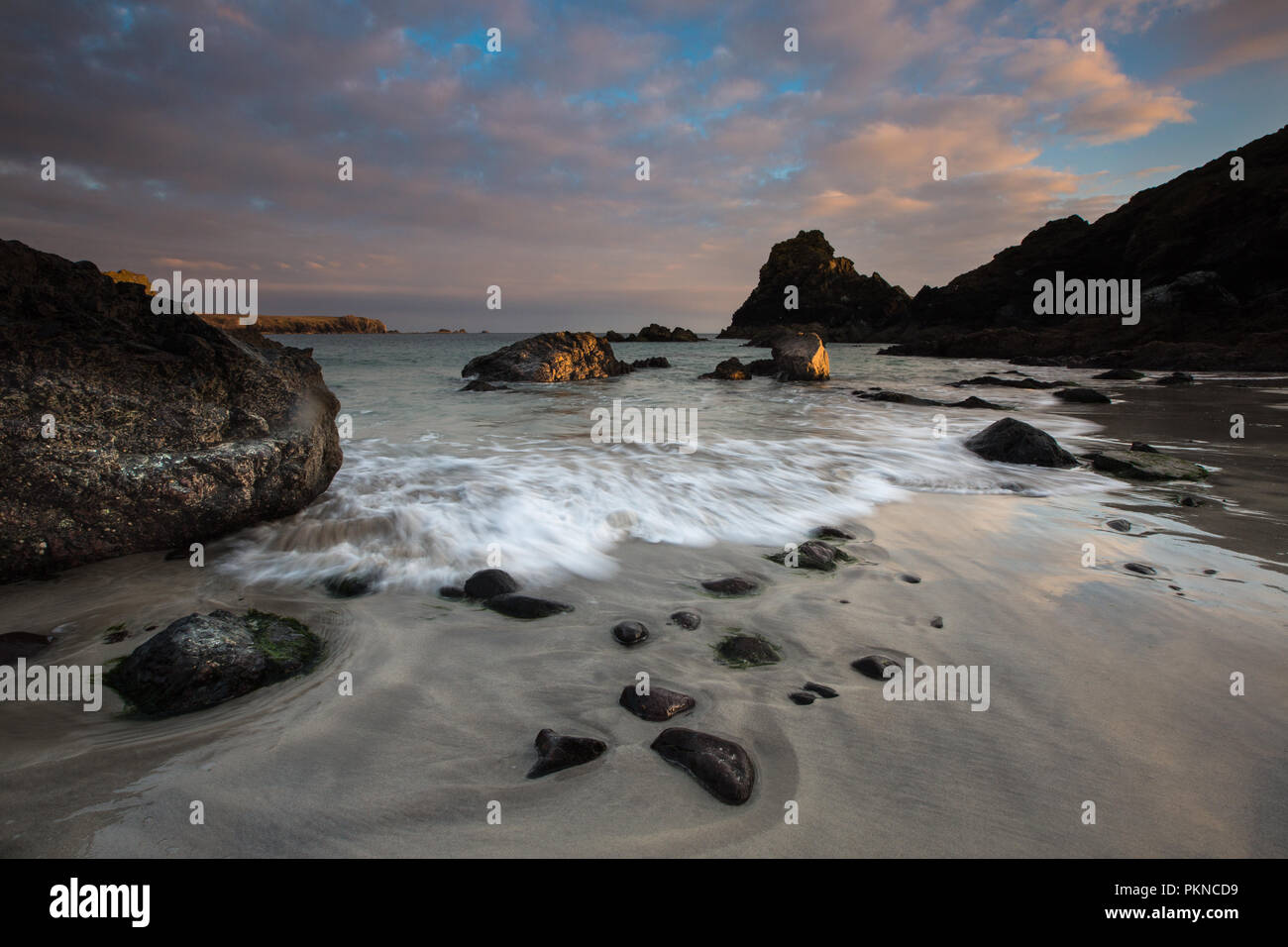 A view of the sandy beach and waves rushing over rocks at Kynance Cove in Cornwall, UK Stock Photo
