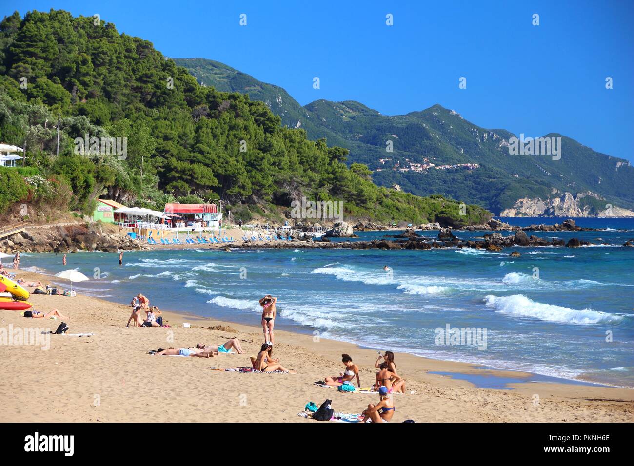 CORFU, GREECE - JUNE 3, 2016: People enjoy the beach in Pelekas, Corfu Island, Greece. 558,000 tourists visited Corfu in 2012. Stock Photo