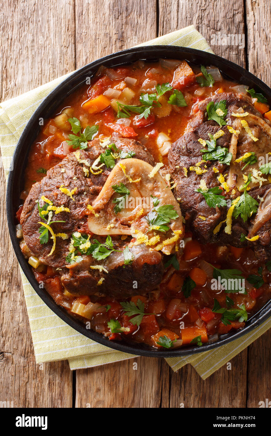 beef shank Ossobuco alla Milanese with gremolata and spicy sauce closeup on the table. Vertical