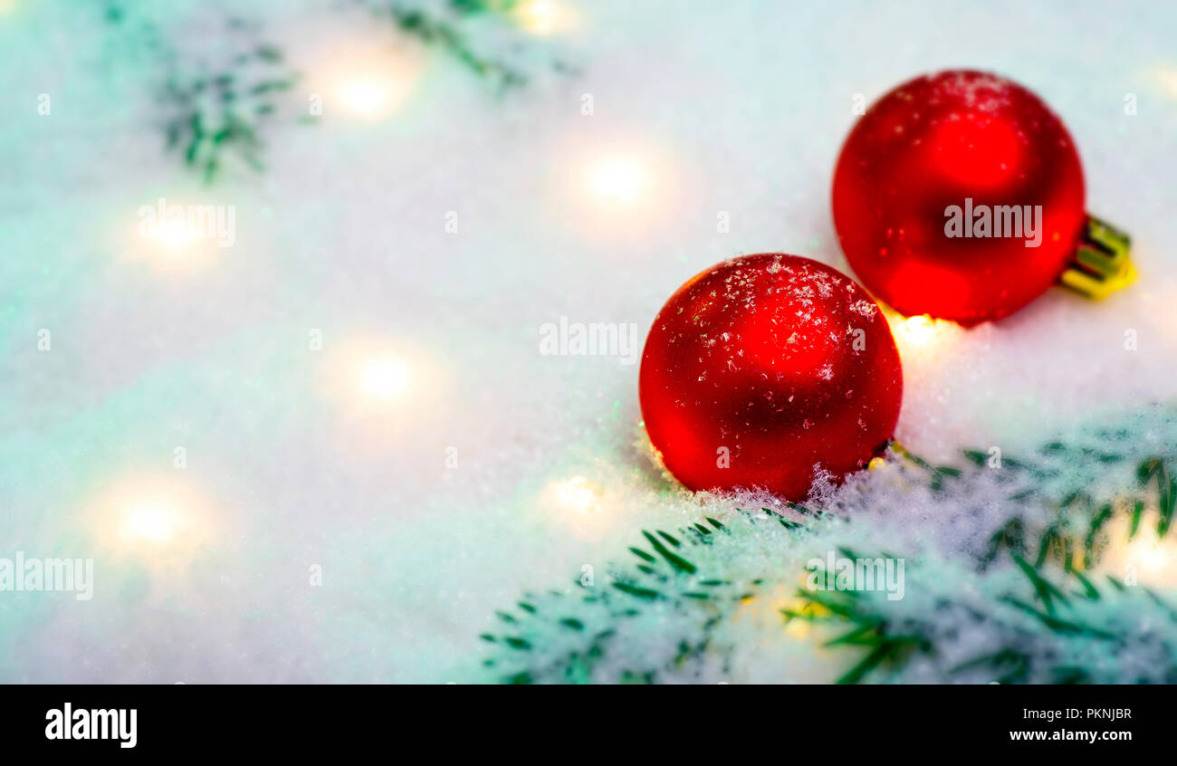 Two red christmas balls with fir branches and lights in the snowsymbol ...