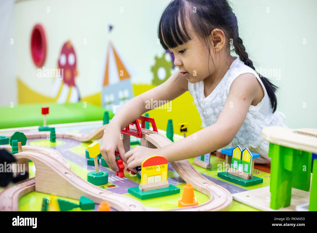 Asian Chinese little girl playing wooden toy train at indoor playground ...