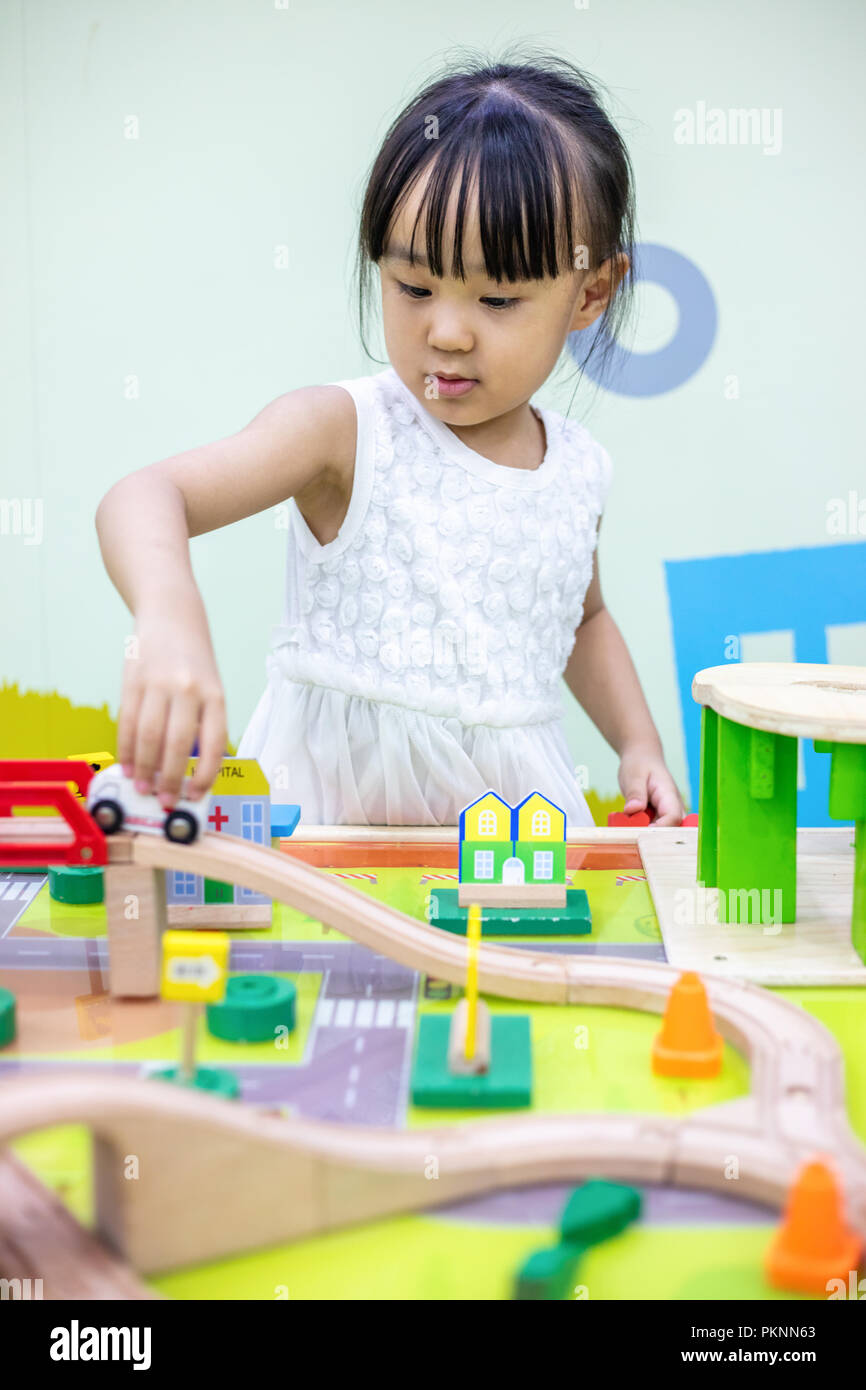 Asian Chinese little girl playing wooden toy train at indoor playground ...